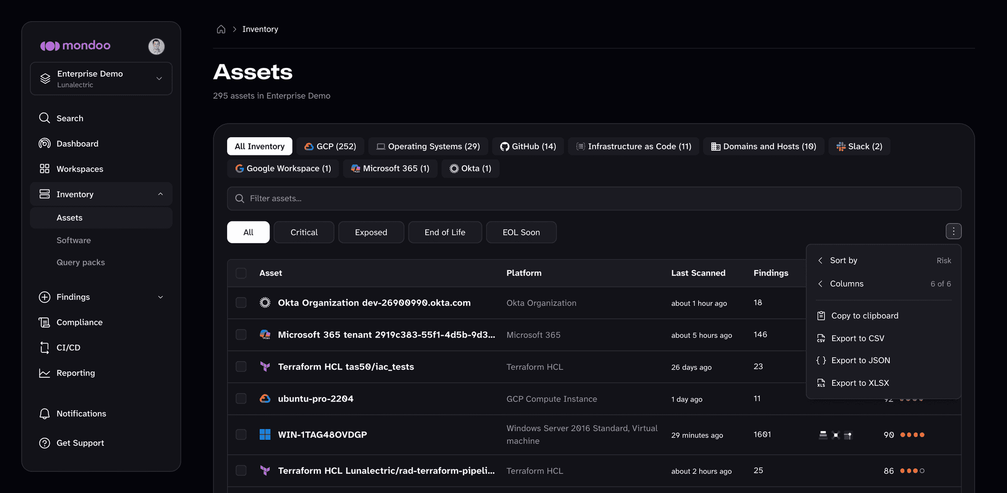 The Assets inventory page with the table menu open, showing Sort by, Columns, Copy to clipboard, Export to CSV, Export to JSON, and Export to XLSX